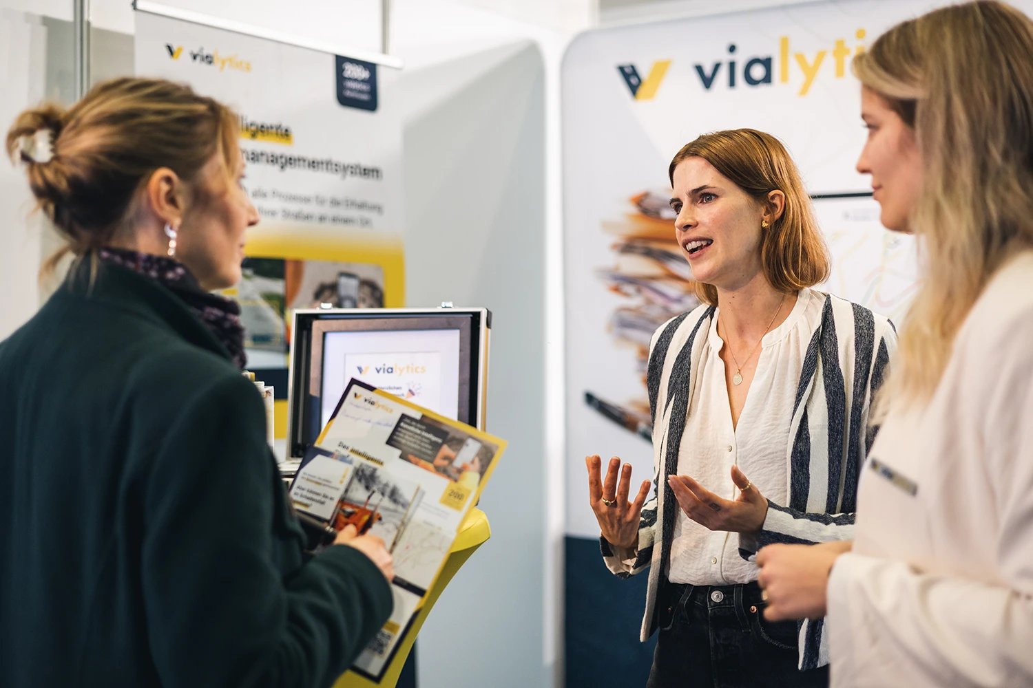 Gesprächssituation zwischen vialytics Mitarbeiterinnen und einer Interessentin am vialytics Messestand
