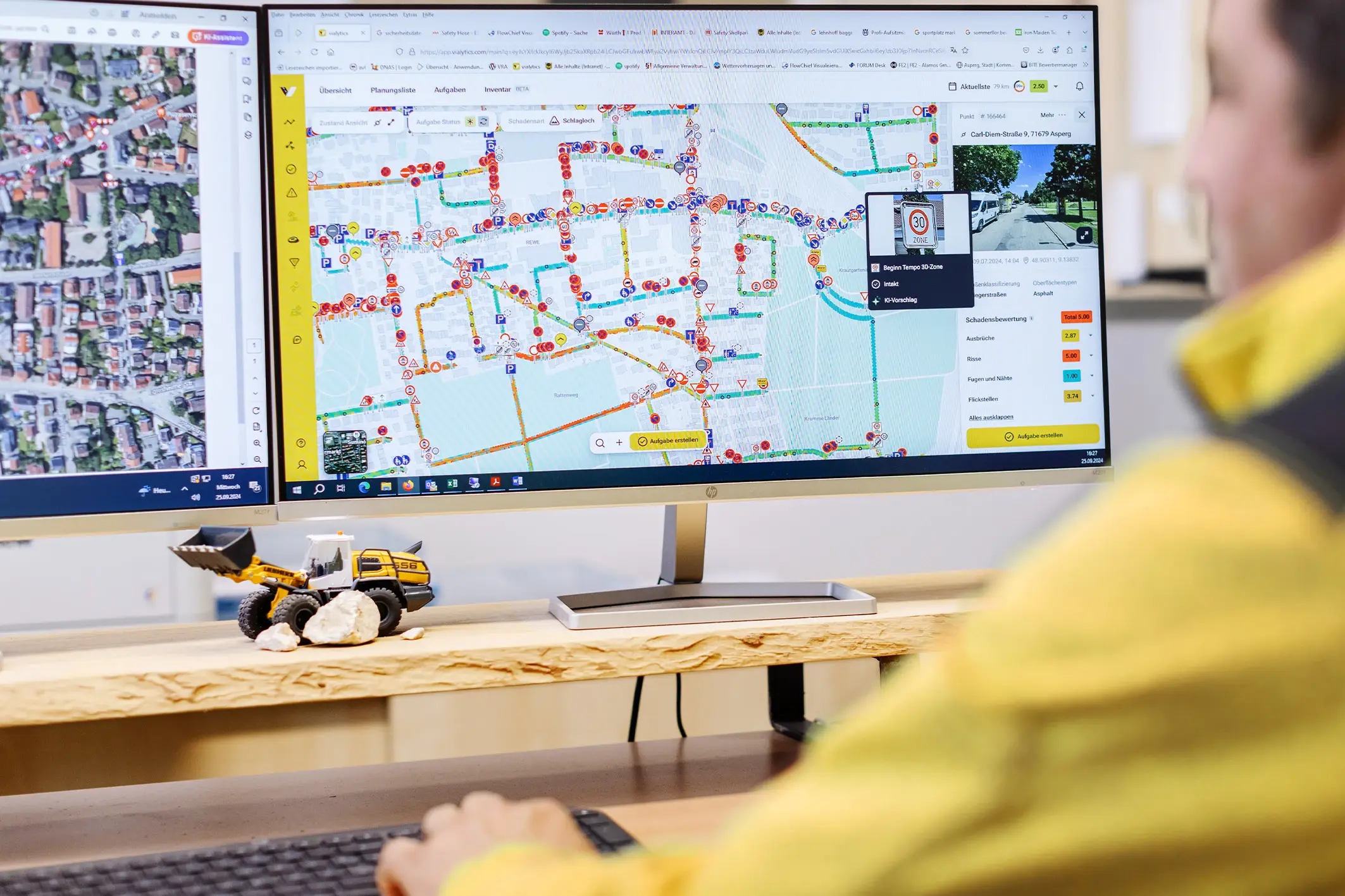 Bauamtsmitarbeiter sitzt vor 2 Monitoren und bedient das vialytics Web System
